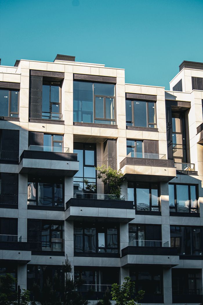 gallery-1 Contemporary apartment building facade with balconies and clear blue sky.