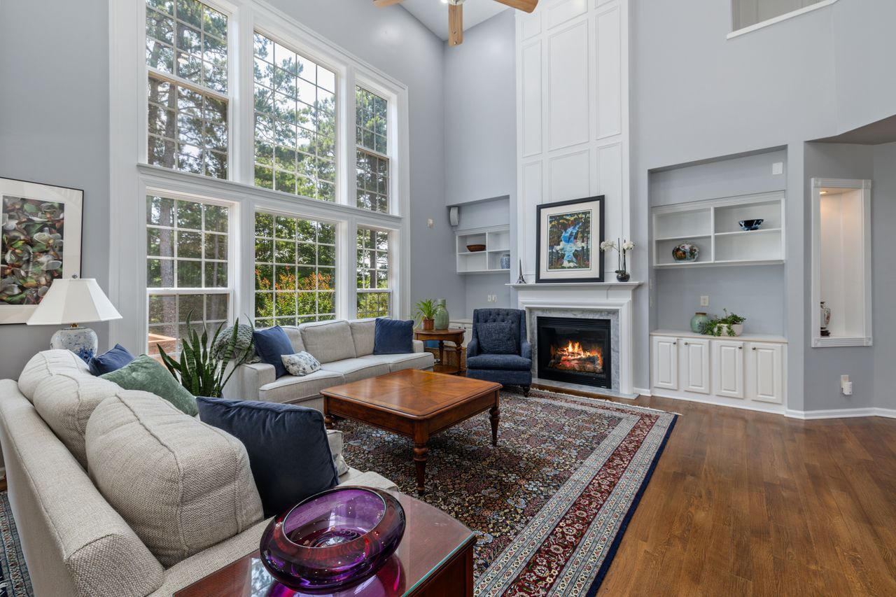 gallery-4 Bright living room with large windows, fireplace, and elegant decor.